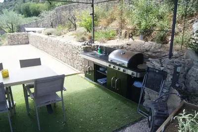a outdoor kitchen with a grill and a table at LOU BRISOU in Saint-Saturnin-les-Apt