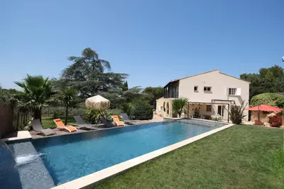 a swimming pool with chairs and a house at Slpendid villa with heated pool and Jacuzzi for 12 people in Saint-chamas in Saint-Chamas