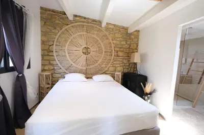 a white bed in a room with a stone wall at Slpendid villa with heated pool and Jacuzzi for 12 people in Saint-chamas in Saint-Chamas