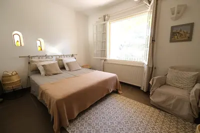 a bedroom with a bed and a window and a chair at Slpendid villa with heated pool and Jacuzzi for 12 people in Saint-chamas in Saint-Chamas