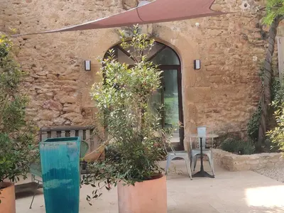 a patio with a table and chairs and an umbrella at Charme et authenticité dans une ferme. in Lourmarin