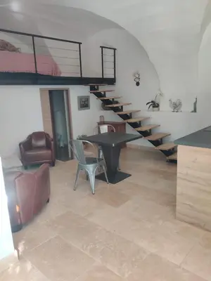 a living room with stairs and a table and chairs at Charme et authenticité dans une ferme. in Lourmarin