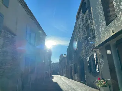 an alley with the sun shining through the buildings at Maison l’Oustaou Cornillonnais in Cornillon-Confoux