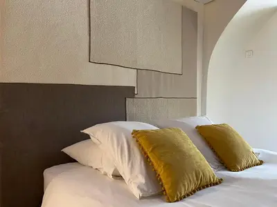 a bed with white sheets and yellow pillows at In Provence Hôtel - Expérience Authentique in Venelles