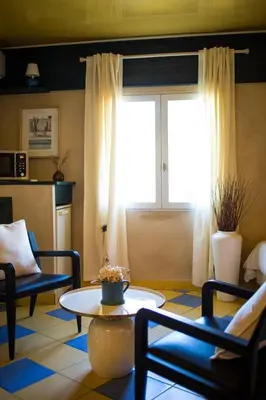 a living room with a table and chairs and a window at In Provence Hôtel - Expérience Authentique in Venelles
