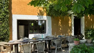 a long wooden table with chairs in front of a building at Le Mas de Bonnety - Magnifique mas 12 personnes au Pied du Mont Ventoux in Saint-Pierre-de-Vassols
