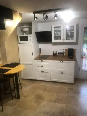 a kitchen with white cabinets and a table at la chambrette in Lincel