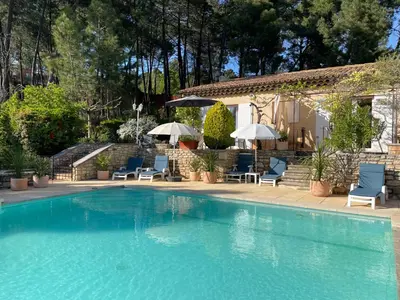 a swimming pool with chairs and umbrellas next to a house at Ô Coeur Des Ocres in Roussillon