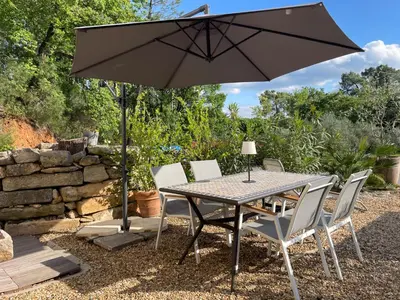 a table and chairs under an umbrella in a yard at Ô Coeur Des Ocres in Roussillon