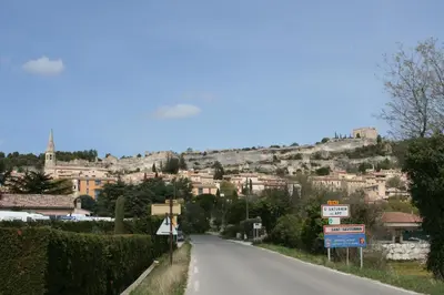 a road in a town with buildings on a hill at Location au cœur du Luberon 2 personnes in Saint-Saturnin-les-Apt