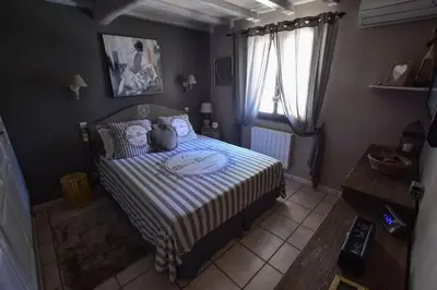 a bedroom with a bed with a striped comforter at Villa le 62 Cazan in Vernègues