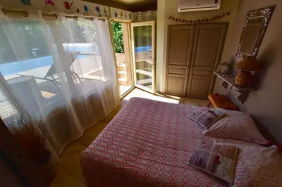 a bedroom with a bed with a pink comforter and a balcony at Villa le 62 Cazan in Vernègues