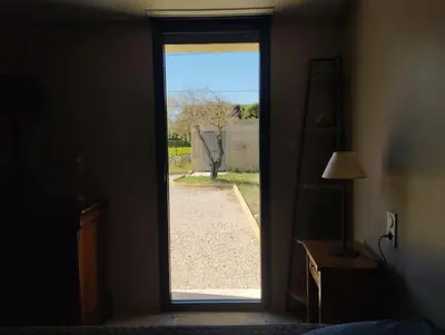 a door leading into a bedroom with a view of a yard at Maisonnette en campagne au calme in Carpentras