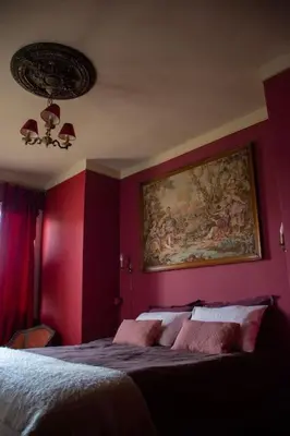 a bedroom with red walls and a painting on the wall at Une pause en Provence au Village des antiquaires de la Gare in LʼIsle-sur-la-Sorgue