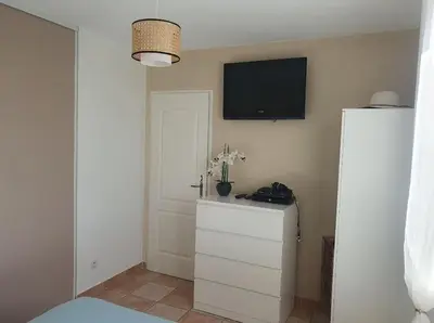 a bedroom with a tv on the wall and a dresser at Maison en Provence avec jacuzzi in Peyrolles-en-Provence