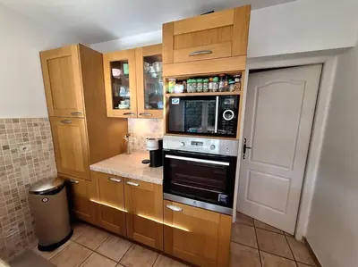 a kitchen with wooden cabinets and a microwave at Maison en Provence avec jacuzzi in Peyrolles-en-Provence