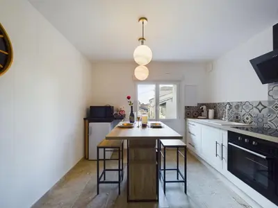 a kitchen with white cabinets and a island with bar stools at Pic love, 2 personnes jacuzzi in Châteaurenard