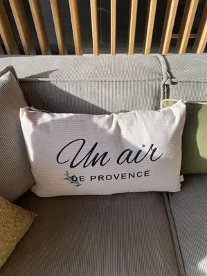 a pillow on a couch with the words un air eyepowered at Gîte Un air de Provence in Eyguières