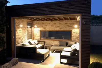 a patio with couches and a tv on a brick wall at Villa Oasis Luxury and Relaxation in Provence in Lambesc