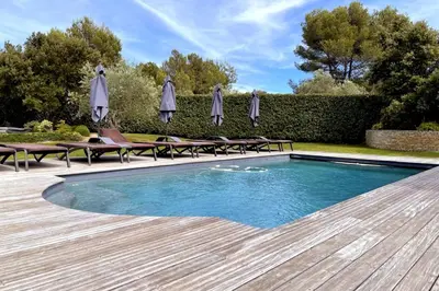 a swimming pool with chairs and umbrellas in a yard at Villa Oasis Luxury and Relaxation in Provence in Lambesc