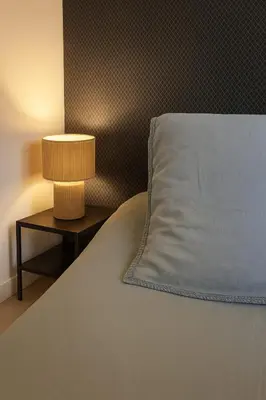 a bed with a blue pillow and a nightstand with a lamp at B&B Lily et Paul in Bédoin
