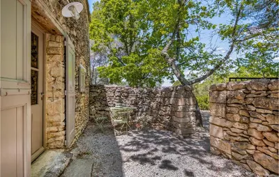 a stone wall with a table in front of a building at Belle Maison À Lacoste in Lacoste