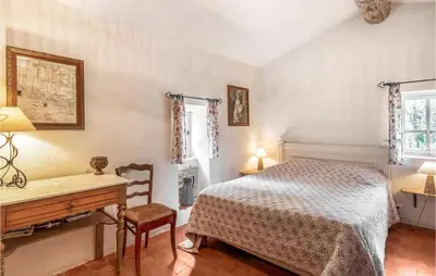 a bedroom with a bed and a desk and a table at Belle Maison À Lacoste in Lacoste