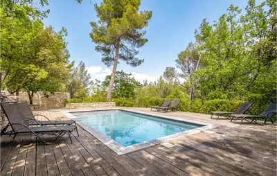 a swimming pool on a wooden deck with chairs around it at Belle Maison À Lacoste in Lacoste