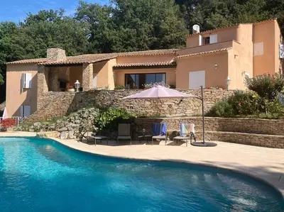 a house with a swimming pool with two chairs and an umbrella at Domaine des Figons in Éguilles