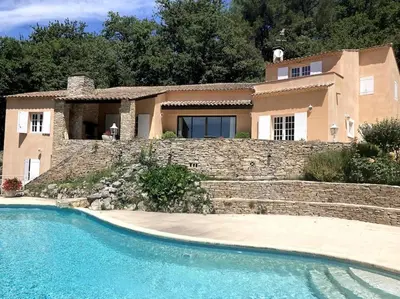 a house with a stone wall and a swimming pool at Domaine des Figons in Éguilles