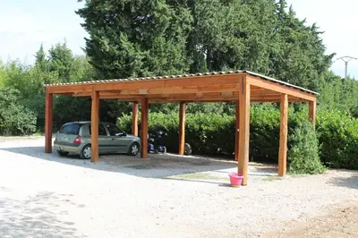 a wooden pavilion with a car parked under it at Le Mas Mérindol Gîte Cerise in Loriol-du-Comtat