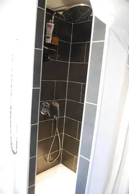 a shower with a black tiled wall with a hose at Superbe mas proche centre-ville in Salon-de-Provence