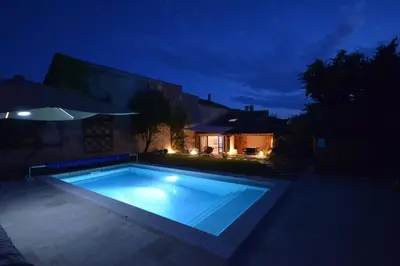 a large swimming pool in a yard at night at La maison d'Anthonie, Roussillon in Roussillon