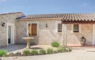 a stone house with a fountain in front of it at La Maoure in Robion en Luberon