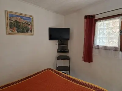 a bedroom with a bed and a tv and a window at Gîte Le Val des Fées classés deux étoiles in Roussillon