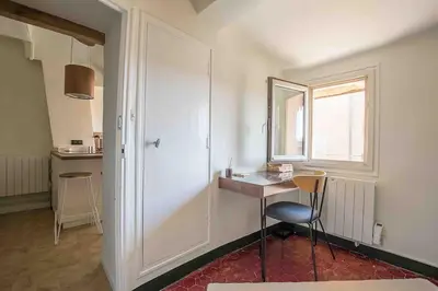 a room with a table and a chair and a window at Petit Cocon avec Vue Dernier Etage - Mazarin 1833 in Aix-en-Provence
