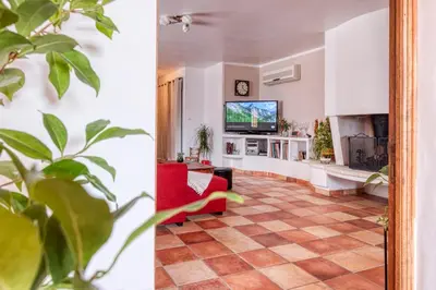 a living room with a red chair and a tv at La Maison du Chapelier in Fontaine-de-Vaucluse