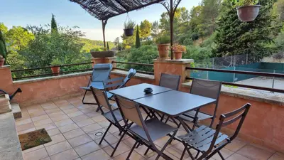 a patio with a table and chairs on a balcony at La Maison du Chapelier in Fontaine-de-Vaucluse