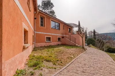 an orange building with a yard next to a sidewalk at La Maison du Chapelier in Fontaine-de-Vaucluse