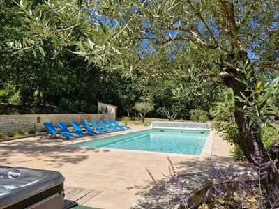 a swimming pool with blue chairs and a tree at Mas Libertino - Villa avec piscine & jacuzzi in Pernes-les-Fontaines
