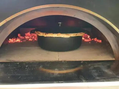 a pizza is being cooked in an oven at Mas Libertino - Villa avec piscine & jacuzzi in Pernes-les-Fontaines