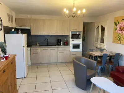a kitchen with a white refrigerator and a table with chairs at La Bastide de Mauragne - Gîte Les Pivoines in Apt