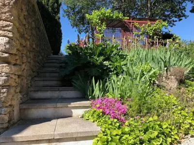 a patio with two chairs and a table and an umbrella at La Bastide de Mauragne - Gîte Les Pivoines in Apt