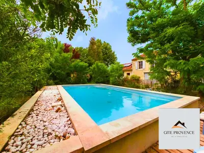 a swimming pool in a yard with rocks and trees at Gîte de la Draillette in Noves