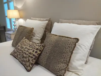 a bed with white pillows and brown and white pillows at Le mas de Roussillon chambre d'hôtes in Roussillon