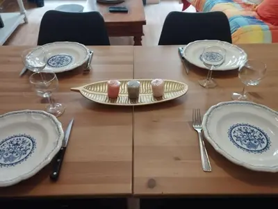 a wooden table with plates and wine glasses on it at Appartement en plein centre. in Carpentras