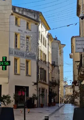 a woman walking down a street in front of a building at Appartement de caractère - CARPENTRAS - Rendez-vous en Provence in Carpentras