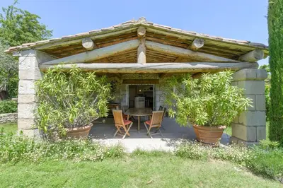a wooden pergola with a table and chairs at Mas des Papillons Gordes in Gordes