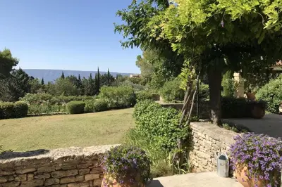 a garden with a stone wall and purple flowers at Mas des Papillons Gordes in Gordes