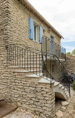 a stone house with a staircase on the side of it at Gordes Le Bastidon in Gordes
